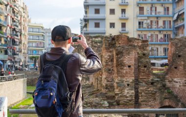 Genç adam, turist, sırt çantası ile bir akıllı telefon üzerinde fotoğraf çekmek