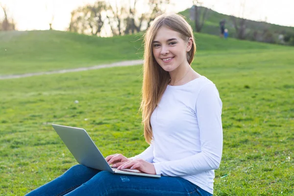 年轻美丽的女学生与笔记本电脑坐在和微笑 — 图库照片
