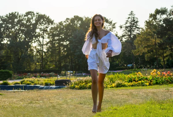 Hermosa joven sonriente corre en ropa blanca en un prado —  Fotos de Stock