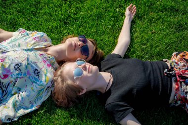 Anne ve kızı güneş gözlüğü çim üzerinde yalan