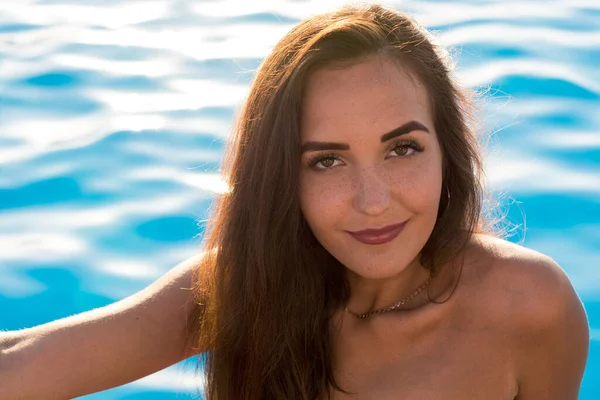 若いです女性の肖像画で長い髪でピンクビキニでプールの近くの端に座っている夏 — ストック写真