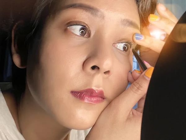 Asia Woman sitting by the mirror and applying makeup.