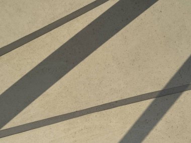 Beton bir duvarın soyut arkaplanı ya da zemin çapraz gölgeli, geometrik şekiller yaratan, minimalizmi temsil eden, modern mimariyi ve doğal ışık ile sanatsal tasarımı temsil eden.