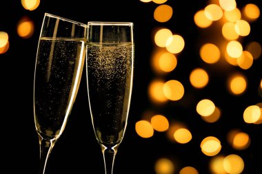 Two champagne glasses toasting on black background with bokeh lights, happy new year clipart