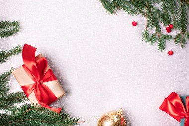 Renkli atlas kurdeleli parlak noel hediyesi ve Noel ağacı dalları ve beyaz gümüş parlak arka planda kırmızı böğürtlenler.