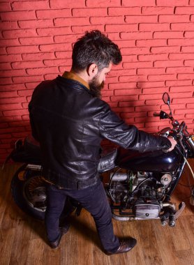 Yenilikçi, vahşi motorcu deri ceketli motosiklet üzerinde arka görüş oturur. Sakallı, motorcu motorlu bisiklet garaj, tuğla duvar arka plan yakınındaki deri ceketli adam. Erkeksi hobi kavramı