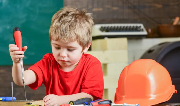 Closeup blond kid in workshop. Boy binding screws to wooden board. Concentrated child learning new skills — Stock Photo, Image