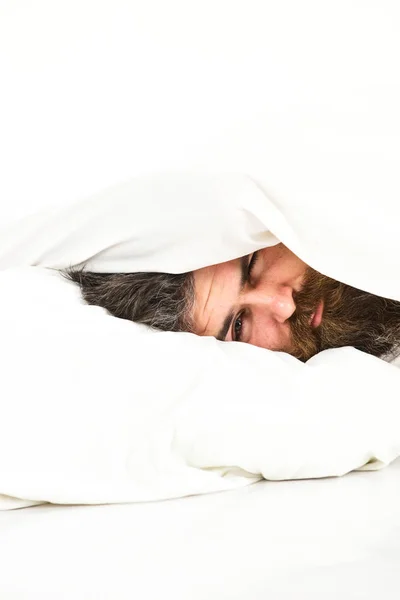 Hombre con la cara somnolienta se encuentra en la almohada debajo de la manta . — Foto de Stock