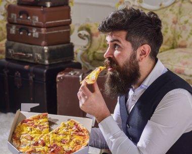 Sakal ve bıyık teslim tutar kutusu lezzetli taze sıcak pizza ile olan adam. Pizza teslim kavramı. Klasik giysiler sürpriz yüzünde aç, maço, ısırıkları dilim pizza, yiyor, iç arka plan