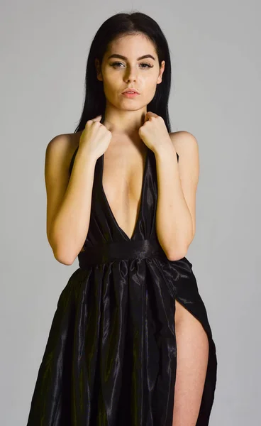 Conceito decotado Sexy. Mulher em elegante vestido de noite preto com decotado, fundo cinza. Menina atraente usa vestido de noite elegante caro com fenda erótica. Senhora, menina sexy no vestido — Fotografia de Stock