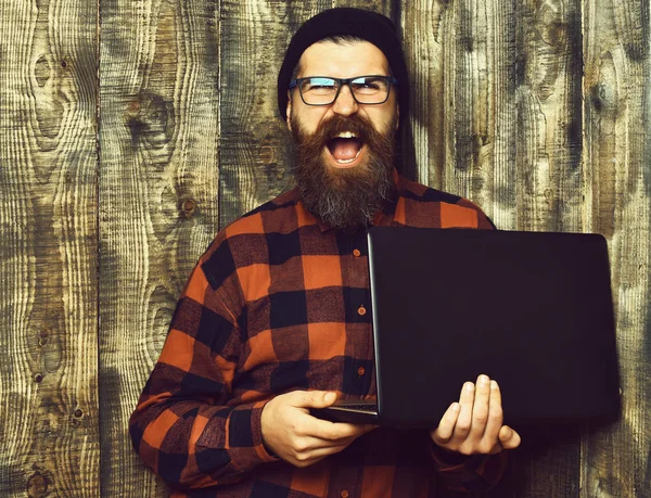 Bearded brutal caucasian hipster holding laptop — Stock Photo, Image