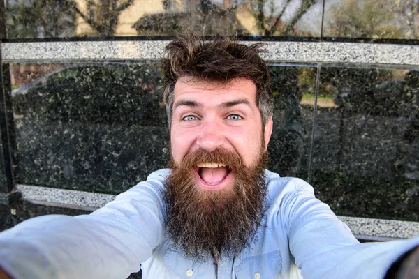 動画ブログのコンセプトです。男は、ひげと口ひげ陽気な微笑んでいる顔、黒い大理石の背景に観光。ヒップスター、逆立つ髪と長いひげ、カメラ目線の観光 selfie 写真を撮る — ストック写真