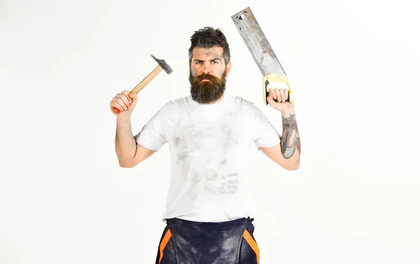 Man met ernstige gezicht houdt saw en hamer. Klusjesman concept. — Stockfoto