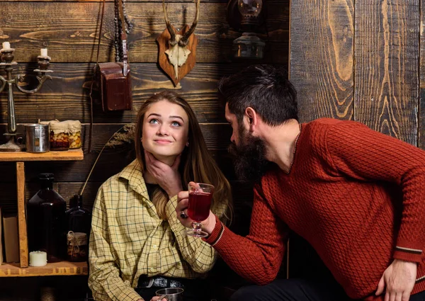 Chica y hombre en caras sonrientes disfrutar de un ambiente acogedor con bebidas calientes. Pareja pasar la noche agradable, fondo interior. Familia, pareja enamorada disfrutar de vacaciones en casa de guardabosques. Concepto de comodidad — Foto de Stock