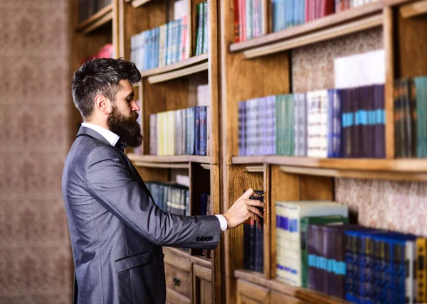 Читатель стоит рядом с книжным шкафом и выбирает книгу . — стоковое фото