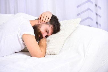 Eller, beyaz perde arka plan üzerinde kulaklarıyla kapsayan yatakta döşeme tişörtlü adam. Arama kavramı uyandır. Sakal ve bıyık maço kalk reddediyor. Sürekli uykulu yorgun yüz adamı uyku
