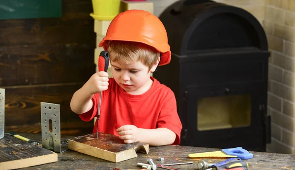 少年はビルダーまたは修理としてプレイするツールします。オレンジ色のハード帽子やヘルメット、研究室のバック グラウンドで少年を子供します。建築や建物内の将来のキャリアについて夢を見ている子。小児コンセプト — ストック写真