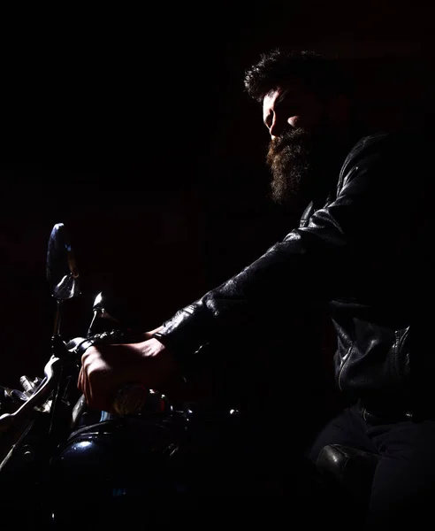 Hipster, motociclista brutal em jaqueta de couro andar de moto à noite, espaço de cópia. Homem com barba, motociclista de jaqueta de couro sentado em moto no escuro, fundo preto. Conceito de cavaleiro nocturno — Fotografia de Stock