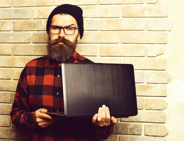 Bearded brutal caucasian hipster holding laptop — Stock Photo, Image