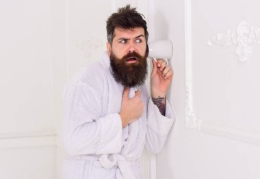 Casusluk, gizli dinleme beyaz iç adam. Gizli ve casus kavramı. Adam sakal ve bıyık kupa duvarının yakınında kullanarak eavesdrops. Hipster katı yüz bornoz içinde gizlice konuşma dinle