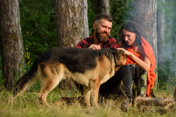 Paar spielt mit Schäferhund im Freien, Waldhintergrund. — Stockfoto
