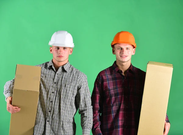 Twin brothers in orange and white helmets. Delivery and warehouse