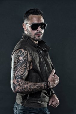 Tıraşsız yüzündeki sakallı dövme modeli. Güçlü silah dövme sakallı adam. Pazı ve triceps dövmeli adam. Moda maço trendy güneş gözlüğü. Moda stil ve trend, vintage filtre.