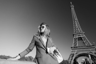 Kız Gezgin poz, Eyfel Kulesi Paris, Fransa. Kadın güneş gözlüğü, güneşli mavi gökyüzü ceket. Tatil, seyahat, gezi. Mimari, cazibe, dönüm noktası. Moda, stil kavramı