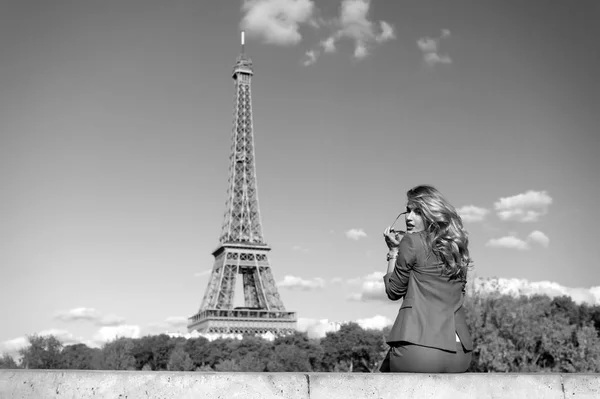 Woman traveler sit at eiffel tower in paris, france. Girl in sunglasses, jacket on sunny blue sky. Architecture, attraction, landmark. Vacation, travelling, trip. Fashion, style concept