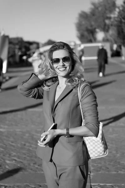 Business woman in blue suit, sunglasses with smartphone and bag smile on street of paris, france. Entrepreneur, entrepreneurship concept. Startup, idea, innovation. Fashion, beauty, style.