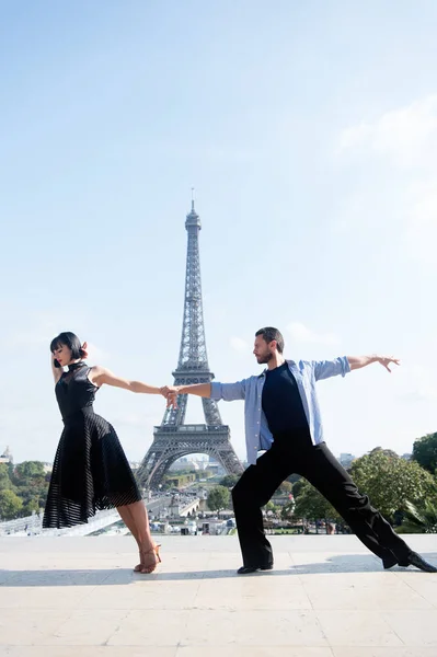 dance couple in front of eifel tower in paris, france. beatuiful ballroom dance couple in dance pose near eifel tower. romantic travel concept. sensual feeling and love