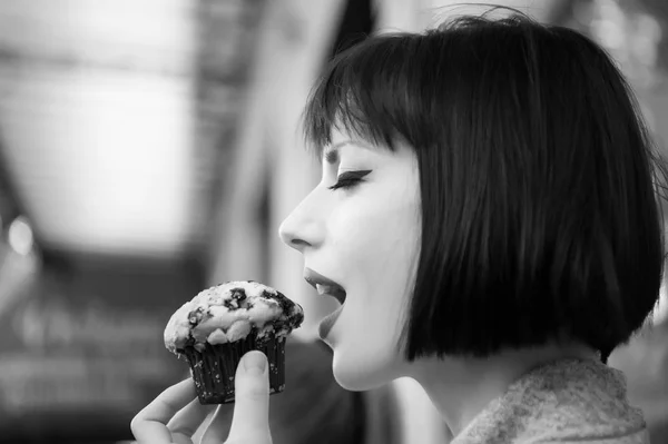 Girl or woman with sensual face eat blueberry muffin in paris, france. Hunger, temptation, appetite concept. Dessert, food, snack, pastry.