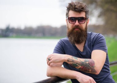 Nehir setin arka plan üzerinde giyer gözlüklü, sakal ve bıyıklı adam. Hippi moda güneş gözlüğü ile kendine güvenen yüzünde. Adam ile şık güneş gözlüğü kendinden emin görünüyor. Erkek moda kavramı
