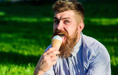 Dondurma külahı sakallı adam. Sakal ve bıyık mutlu yüz yalıyor dondurma, defocused arka plan, çim üzerinde olan adam. İncelik kavramı. Dondurma, çimlerin üzerine oturur iken uzun sakallı adam yiyor