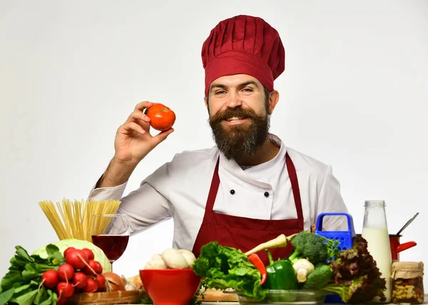 Kocken holding röd tomat. Mannen i röd mössa — Stockfoto