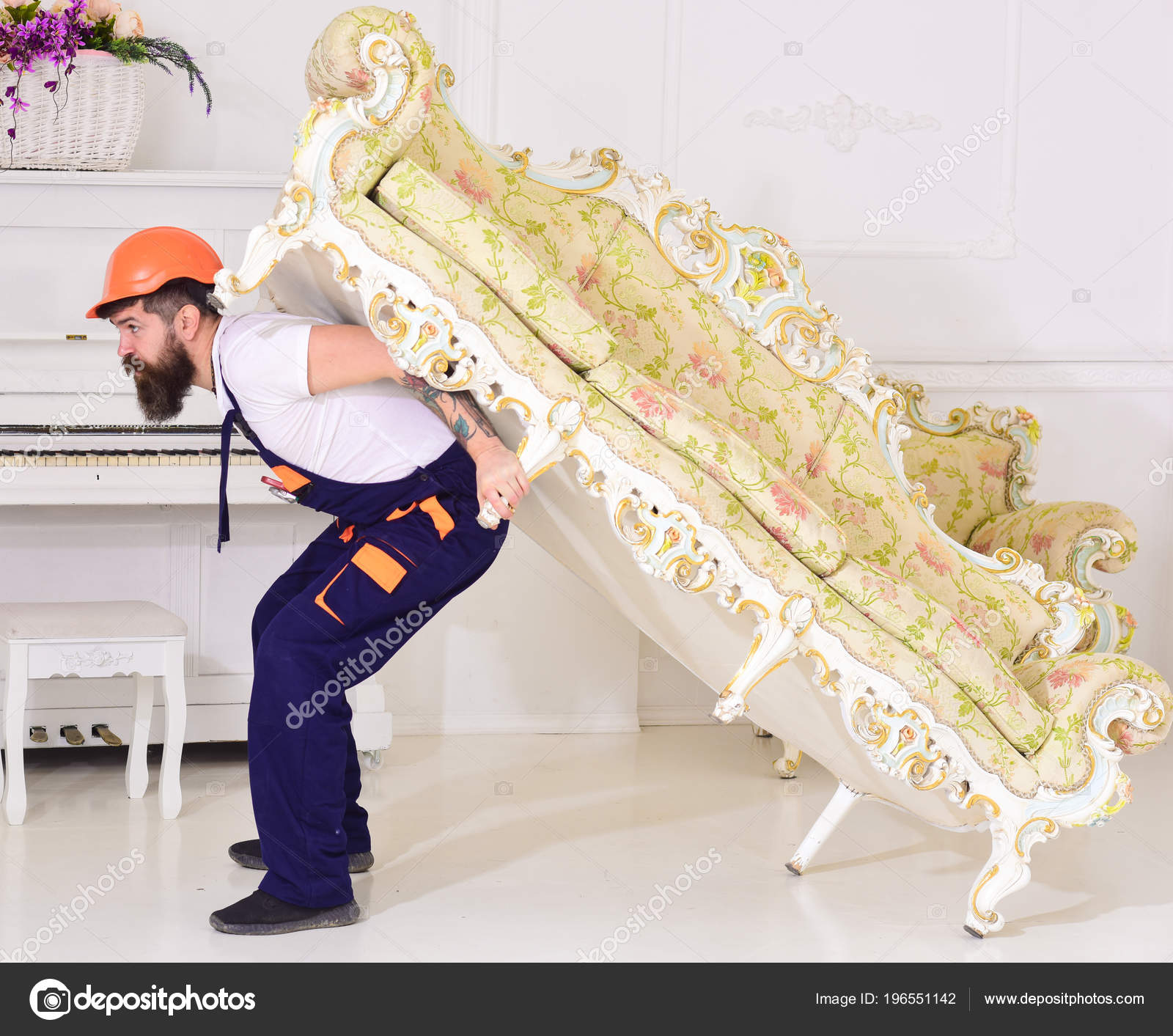 搬迁概念。快递送货上门, 搬迁时送家具。装载者移动沙发, 沙发。人与胡子, 工作者在工作服和盔甲运载沙发在后面, 白色背景——图库图片©