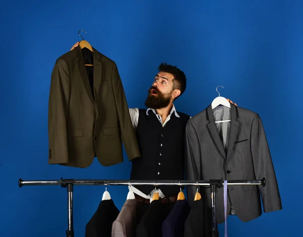 Designer makes choice near clothes hangers. Tailoring and design