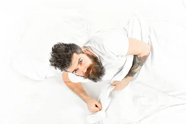 Man with sleepy face get up on bed, white sheets