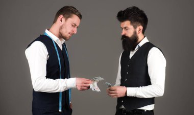 Sakallı bir adam mezurayla maçoya ödeme yapıyor..