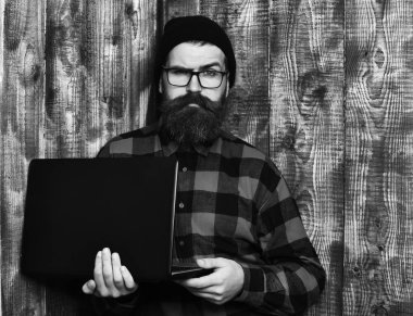 Kaba sakallı, beyaz tenli hippi dizüstü bilgisayar tutuyor.