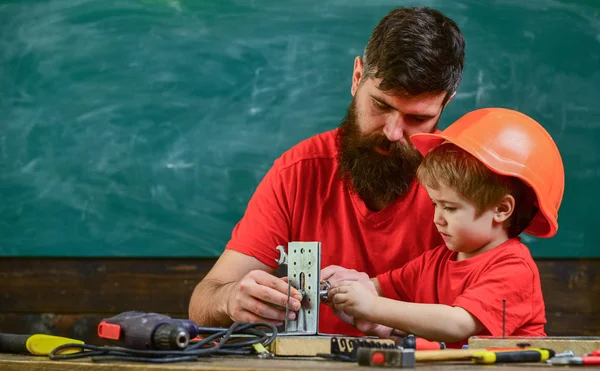 Mens kavramı çalışır. Evlat, Çocuk koruyucu kask içinde el ile onarım, babamla mı el sanatları yapar. Baba sakal ve araçlarını kullanmak için sınıf öğretim küçük oğlu kara tahta arka plan ile