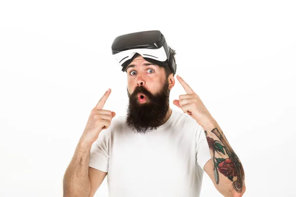 Mann mit Bart und Schnurrbart hält vr Brille, weißer Hintergrund. vr Technologiekonzept. Typ mit Vr-Brille oder kopfmontiertem Display. Hipster auf aufgeregtem Gesicht zeigt mit Zeigefinger auf Gadget — Stockfoto