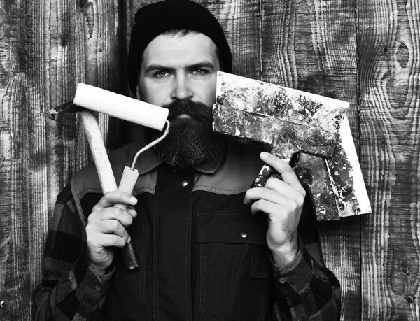 Γενειοφόρος οικοδόμος άνθρωπος κρατώντας διάφορα δομικά εργαλεία με σοβαρό πρόσωπο — Φωτογραφία Αρχείου