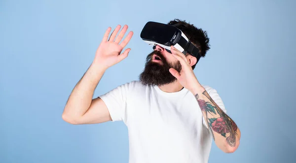 Homem com barba em óculos VR, fundo azul claro. Conceito de dispositivo VR. Cara com cabeça montada exibir interagir em realidade virtual. Hipster no rosto ocupado explorando a realidade virtual com gadget moderno — Fotografia de Stock