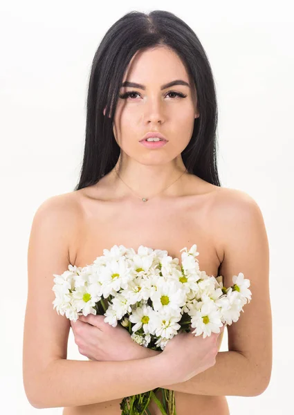 Skin care concept. Woman with smooth healthy skin looks attractive. Girl on calm face stands naked and holds chamomile flowers in front of chest. Lady covers breasts with flowers, isolated on white — Stock Photo, Image