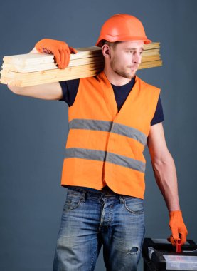 Ustalığının kavramı. Marangoz, woodworker, işçi, Oluşturucu meşgul yüz taşıdığı ahşap kirişler omuz üzerinde. Dostum, tamirci kask, kask içinde tutan araç kutusu ve ahşap kirişler, gri arka plan