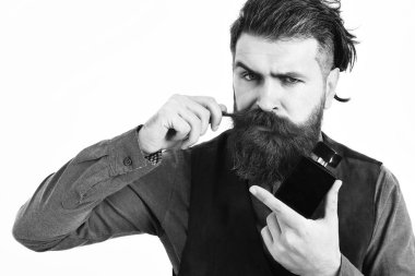 Sakallı adam ciddi bir parfüm tutuyor.