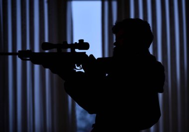 Pencerenin önünde kurban nişan maço silüeti. Avcı, asker silah çekimden önce nişan ile. Tetikçi kavramı. Adam silah, tüfek karanlık iç arka planda tanınmaz