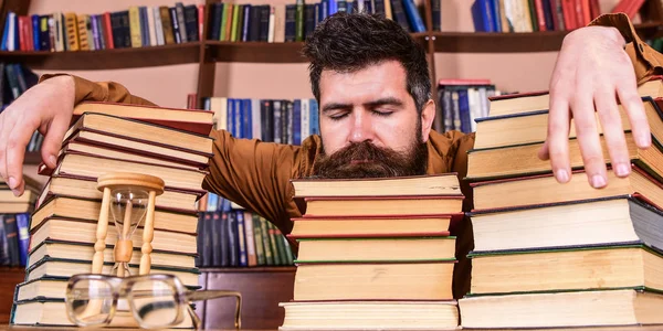 Ο άνθρωπος στον ύπνο πρόσωπό lay μεταξύ σωρούς από βιβλία, κοιμηθείτε ενώ σπούδαζε στη βιβλιοθήκη, ράφια σε φόντο. Δάσκαλος ή μαθητής με γενειάδα κοιμηθείτε σε βιβλία, defocused. Overstudied έννοια — Φωτογραφία Αρχείου