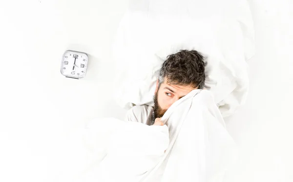 Guy hides face under blanket. Morning and wake up concept.